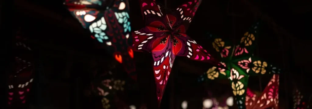 Colorful patterned star lanterns hanging in a dark restaurant setting for Christmas decorations