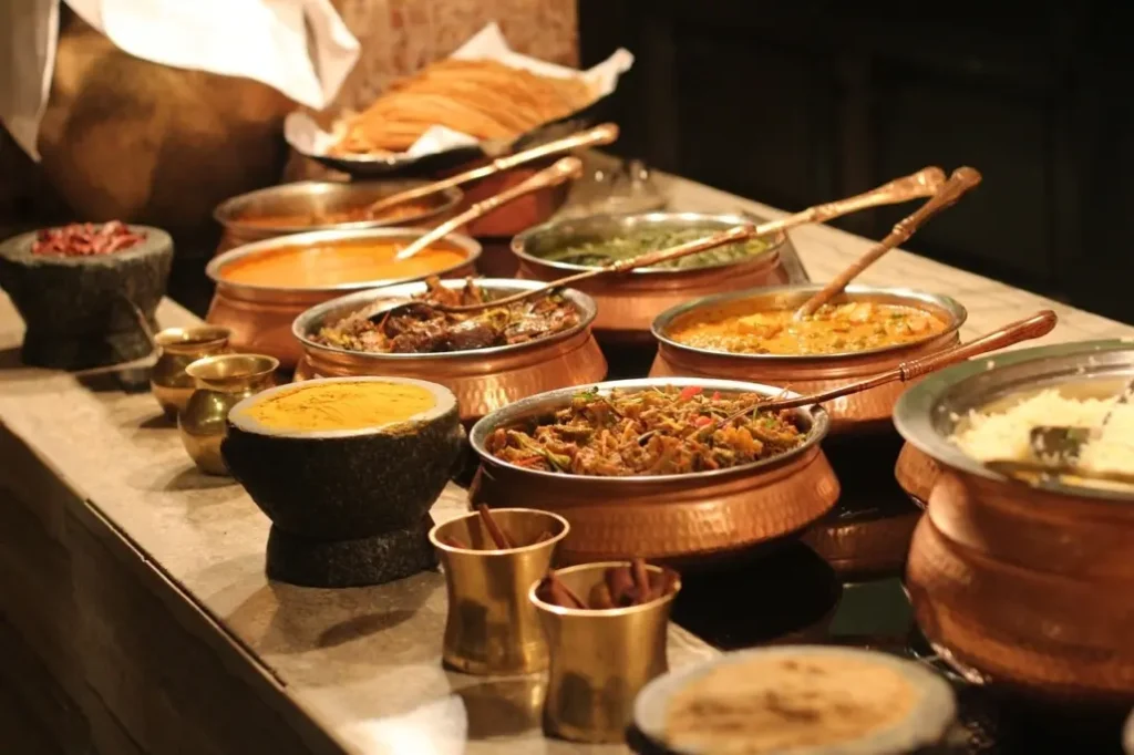 Indian buffet spread with curries, rice and breads in copper serving bowls