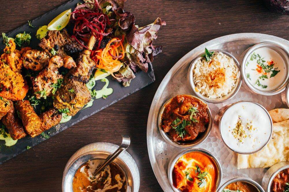 A platter of grilled Indian kebabs with salad and a thali of curries, rice, and naan