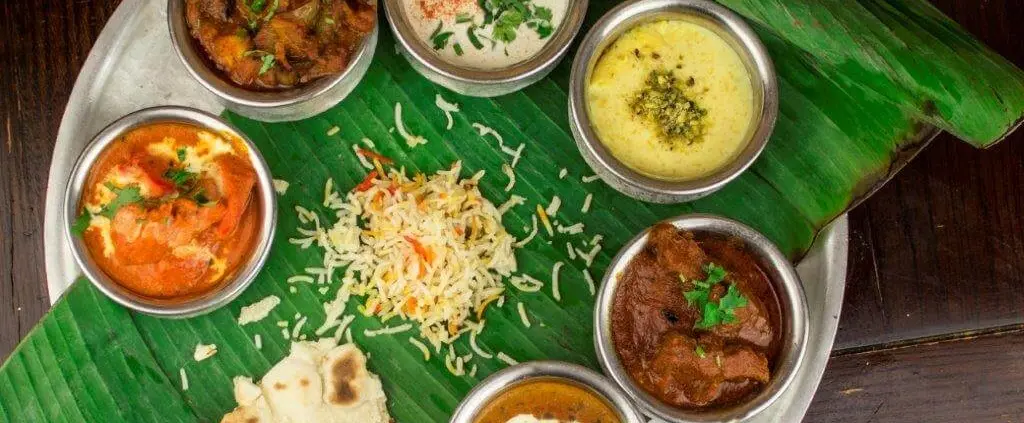 A festive Indian thali on a banana leaf with rice, naan, and assorted curries from Itihaas restaurant.