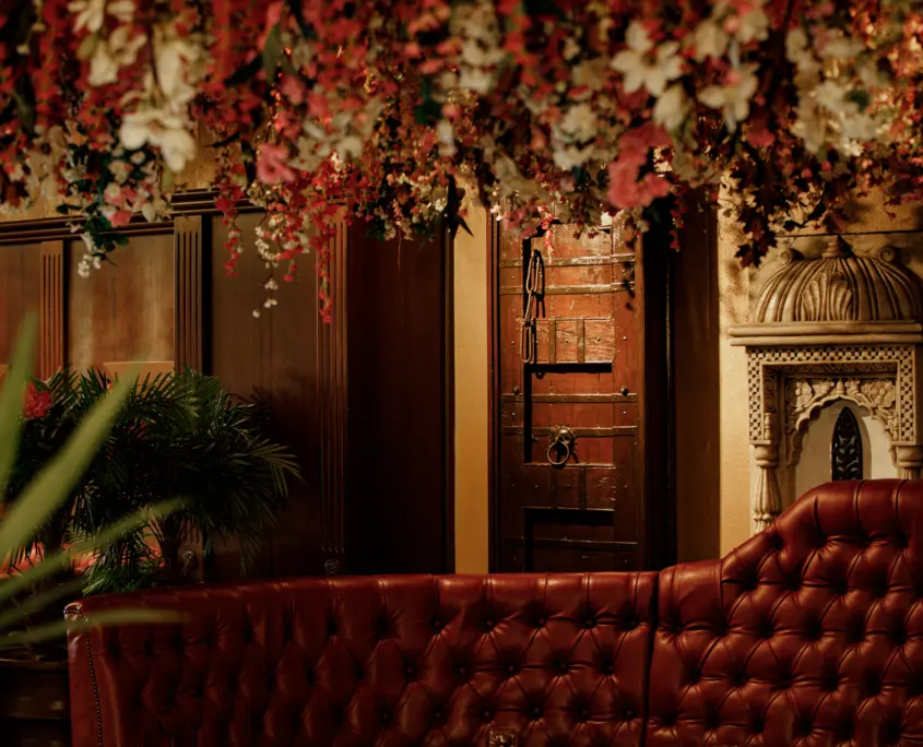 Red tufted leather sofa in Itihaas Indian restaurant, Birmingham, with hanging pink and white floral arrangement